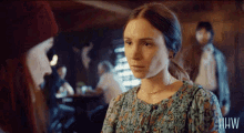 a woman in a blue floral dress with the letters hw on the bottom right