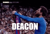 a man in a blue shirt is holding up a jersey with the word deacon on it