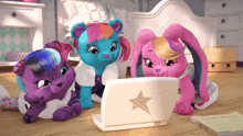 three stuffed animals are looking at a laptop with a star on the front
