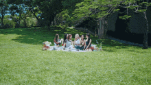a group of women are sitting on a blanket in a park
