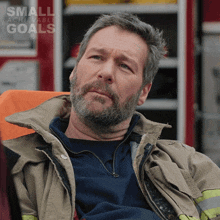 a man in a fireman 's uniform is sitting in an ambulance with the words small achievable goals on the bottom