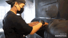 a man wearing a mask and gloves is cooking ribs in a smoker made in animatica