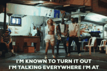 a group of people are dancing in front of a building with the words i 'm known to turn it out