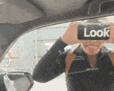 a woman is taking a picture of herself with a phone that says look on it