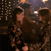 two women are hugging in front of a drum set with the word tama on it