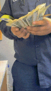 a man in a blue shirt is holding a large stack of money