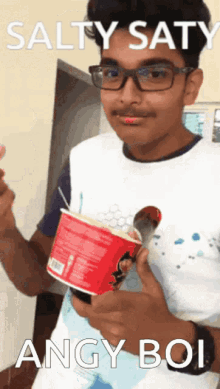 a young man holding a cup of ice cream with the caption salty saty angy boi on the bottom