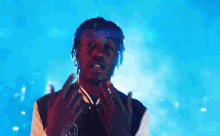 a young man is standing in front of a blue background and making a funny face .