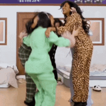 a woman in a leopard print pajamas is hugging two other women .