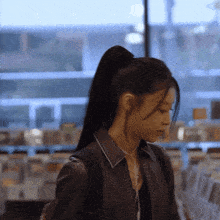 a woman wearing a ponytail and a black jacket