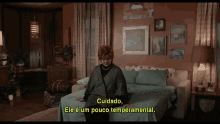 a woman is sitting on a bed with a caption that says cuidado ele e um pouco temperamental