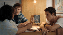 a group of people sit at a table with a menu on the wall behind them