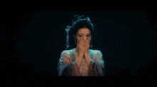 a woman is covering her face with her hands