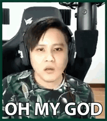 a man wearing headphones is sitting in a chair in front of a microphone and making a funny face .