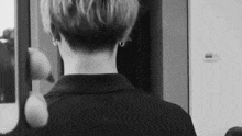 a black and white photo of a person looking at their neck in a mirror .