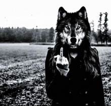 a black and white photo of a woman with a wolf mask on giving the middle finger