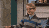 a young boy wearing glasses and a striped sweater is making a face .
