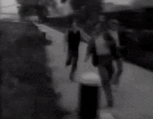 a blurry black and white photo of a group of people standing on a sidewalk .