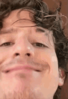 a close up of a man 's face with a beard and curly hair making a funny face .
