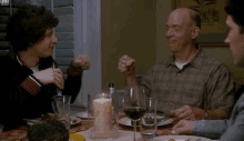 a group of people are sitting at a table with plates of food and glasses of wine