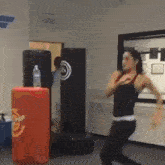 a woman is standing in front of a punching bag that says ' fighter ' on it