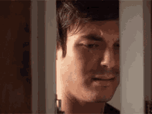 a close up of a man 's face looking out of a doorway .