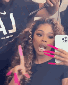 a woman with long pink nails is taking a picture of herself in the mirror .