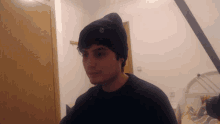 a young man wearing a black beanie with the letter x on it