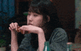a woman sitting at a table with her eyes closed eating a piece of food