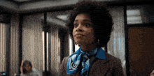 a woman with an afro wearing a blue scarf with the letter g on it