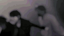 a blurry picture of two people standing next to each other in a dark room .