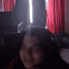 a woman in a dark room with red curtains