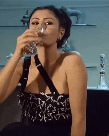 a woman in a black dress drinks from a glass