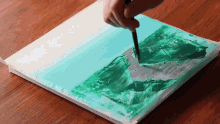 a person is painting a picture on a canvas with green paint