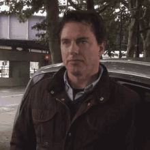 a man standing in front of a car with a red light in the background