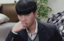 a young man in a suit is sitting on a couch