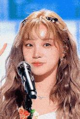 a close up of a woman singing into a microphone with flowers in her hair