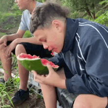 a boy is eating a slice of watermelon outside