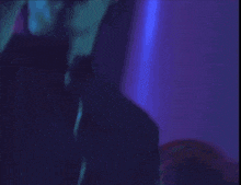 a woman covering her face with her hand in a purple light