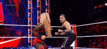 two women are dancing in a wrestling ring during a match .