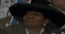 a woman wearing a hat and earrings is sitting in a stadium and making a funny face .