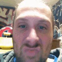 a man with a beard is making a funny face in front of graffiti on the wall