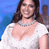 a woman wearing a white blouse and a necklace with the name devasena on the bottom