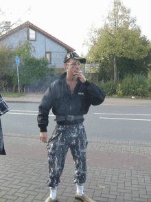 a man smoking a cigarette while wearing a black jacket with the word army on the front
