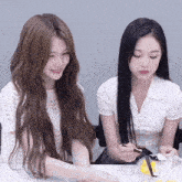 two girls are sitting at a table and one is holding a spoon