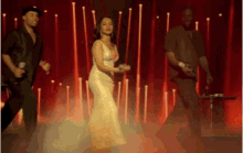 a woman in a long white dress is dancing on a stage with two men