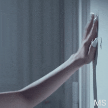 a woman 's hand is reaching for a hook on a wall with ms written on the bottom