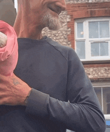 a man with a tattoo on his arm is holding a dog in a pink blanket