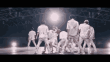 a group of young men are dancing on a stage in front of a light .