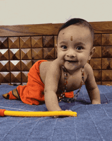 a baby is crawling on a bed with a yellow stick in front of him